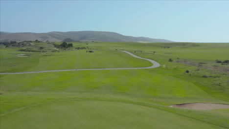 aerial drone shot of a lawnmower cutting the grass at a gold course in half moon bay, california, usa