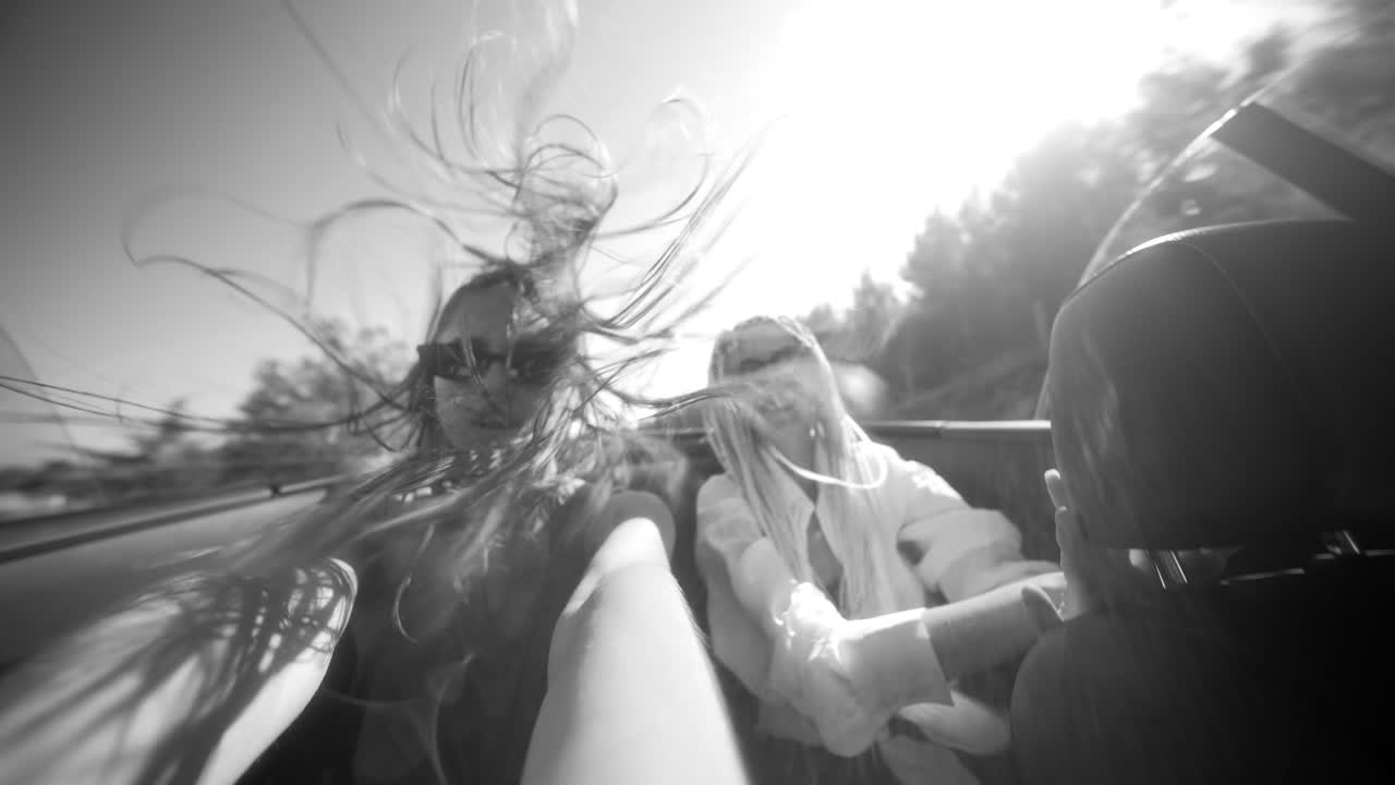 Two happy young women enjoying a road trip in a convertible on a sunny day