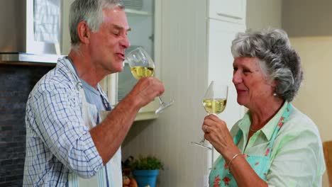 Senior-couple-interacting-while-having-wine-in-kitchen-4k