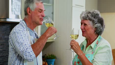 senior couple interacting while having wine in kitchen 4k