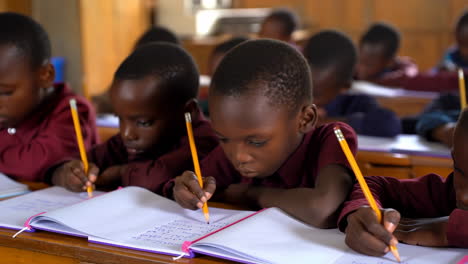 young african students writing in notebooks in a classroom
