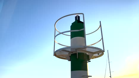 Small-lighthouse-beacon-in-the-morning-light,-standing-tall-on-the-coastline