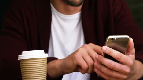 Hombre-Usando-Un-Teléfono-Móvil-En-Una-Cafetería