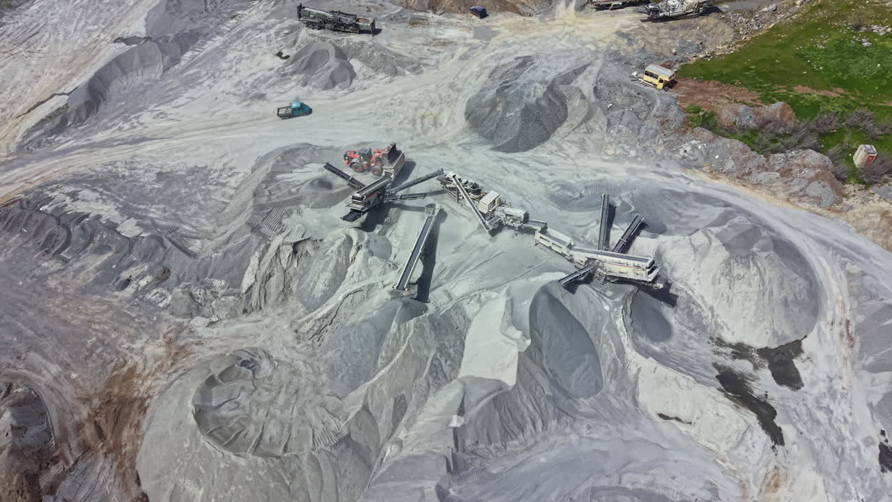 Granite quarry site with machinery and stockpiles during day light hours in a working environment