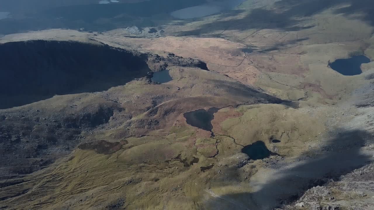vista aérea de abajo hacia arriba de enormes montañas en un día soleado con algunos lagos en el medio