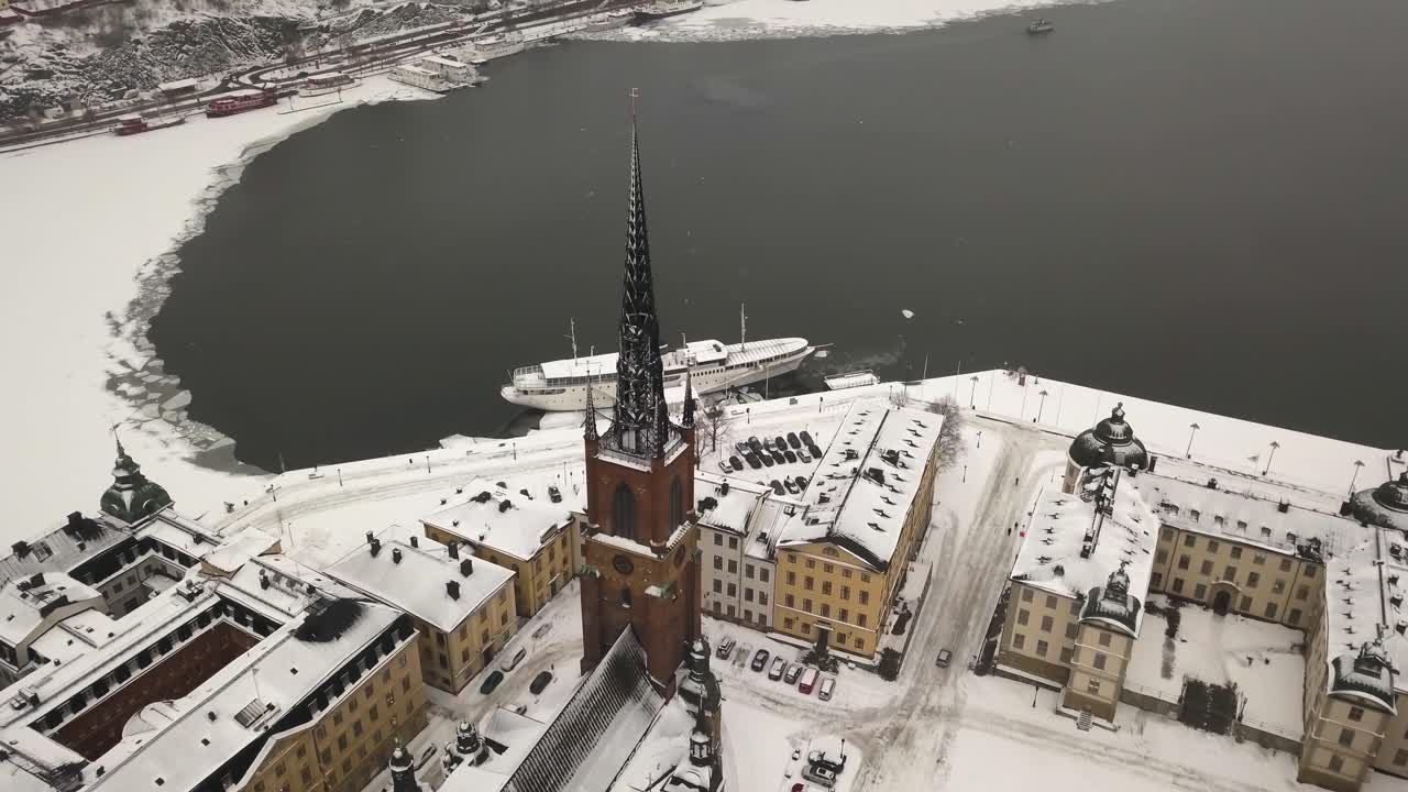 Wide aerial shot of Stockholm city scene with panoramic view of Riddarfj&auml;rden while zooming in on famous church of Riddarholm