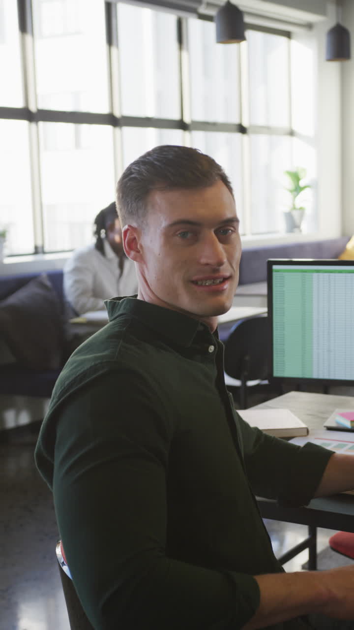 video vertical del retrato de un feliz hombre de negocios caucásico mirando a la cámara en la oficina