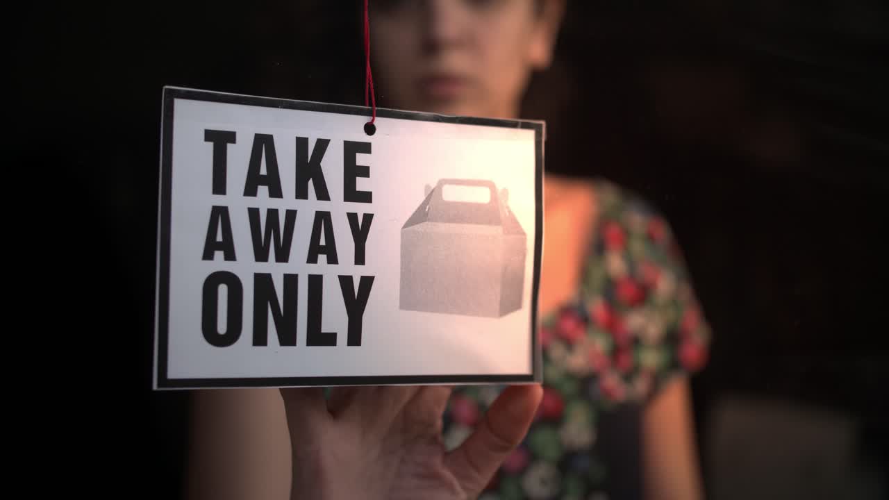 Hænder, der vender et butiksskilt fra "Åbent" til "Take Away"