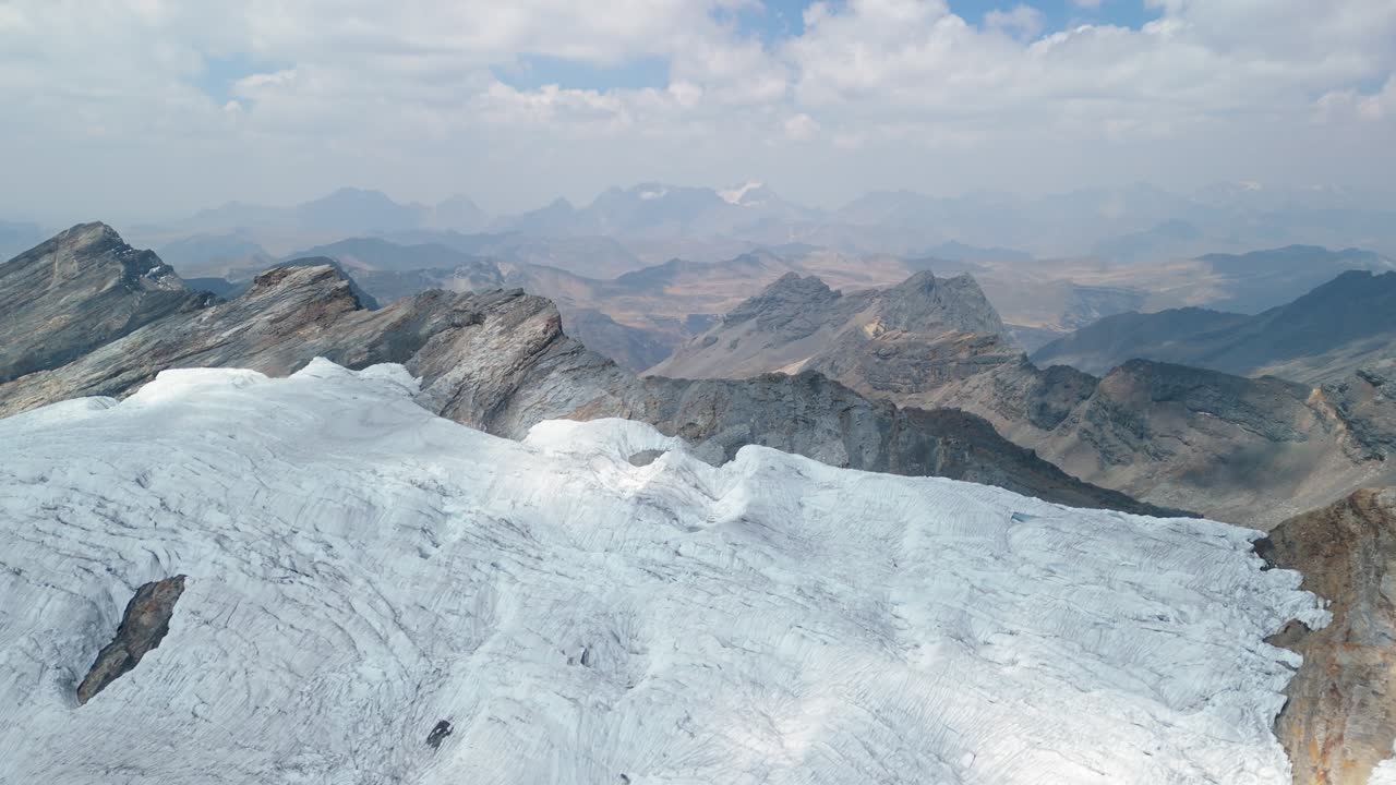 A spectacular aerial view rises vertically over the vast, icy expanse of the Pastoruri Glacier, revealing the full scale of the mountain landscape in the Peruvian Andes