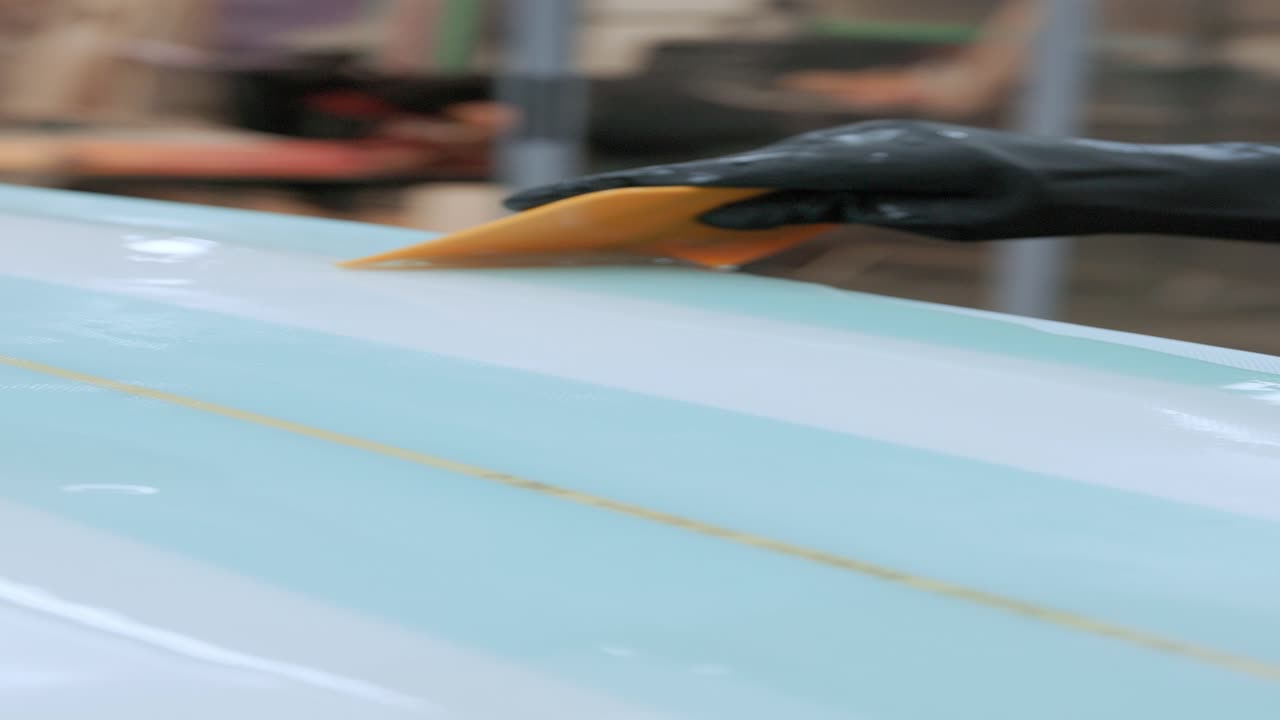 hombre recortado sin rostro pegando película en la tabla de surf