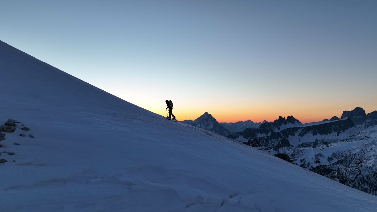 alpinista escalando una montaña con esquís antes del amanecer