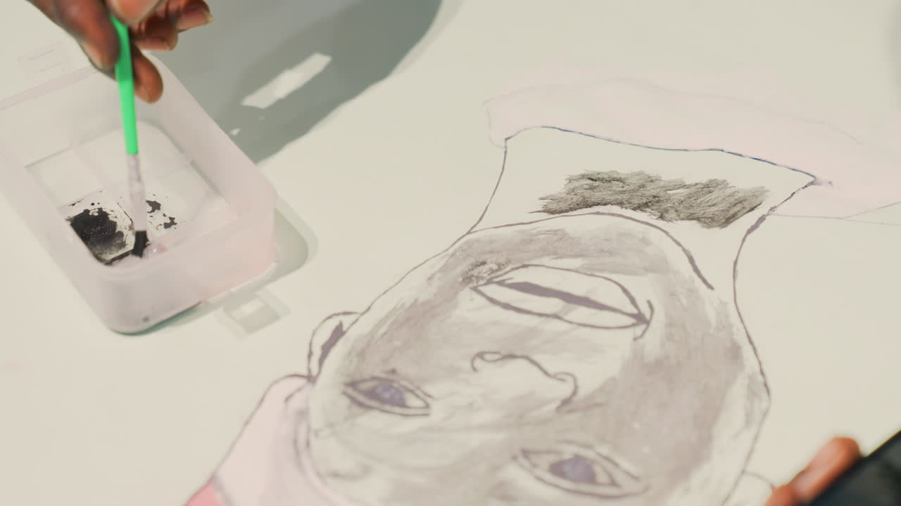 Hand ovanifrån applicerar svart bläck på ett porträtt i svart på vitt papper. Illustratören doppar ett grönt verktyg i en behållare, skapar mörk hårtextur med stippling och prickad kontur, med en smartphone som referens i närheten