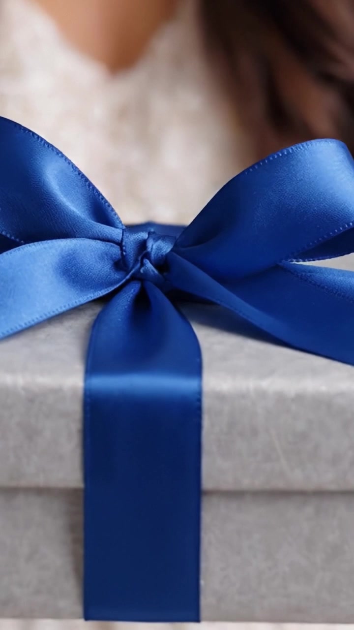 Una scatola regalo splendidamente incartata e decorata con un elegante nastro blu, che simboleggia l'emozione e la gioia di fare e ricevere regali in occasioni speciali