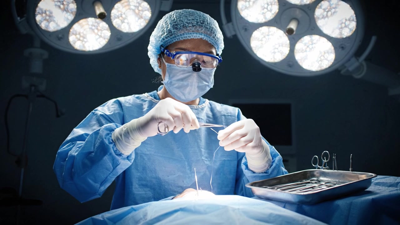 Kirurgisk procedure i gang: Medicinsk professionel udfører operation med præcision under skarpe operationslamper og korrekt sterilt tøj i et operationsstue-miljø.