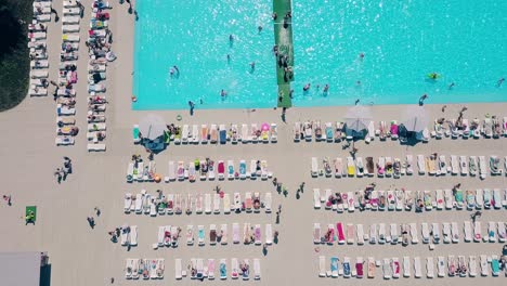 aerial flying over the beach a lot of people are sunbathing swimming in the pool