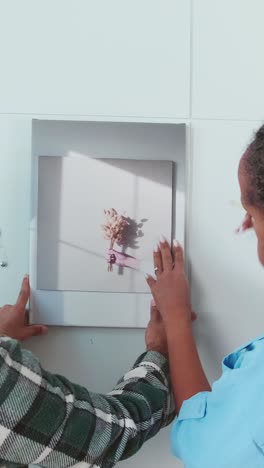 young african american woman and man together hang stylish picture on wall