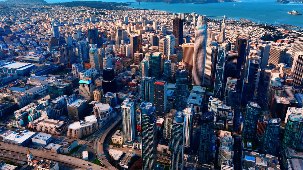 Vista aérea panorâmica do distrito financeiro de São Francisco com arranha-céus, a Pirâmide Transamerica e o sistema de autoestradas que se estende em direção aos arredores da cidade e à baía.