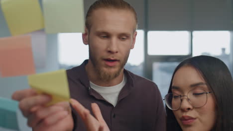 Angry-girl-disagreeing-partner-at-sticker-wall-place-portrait.-Coworkers-arguing