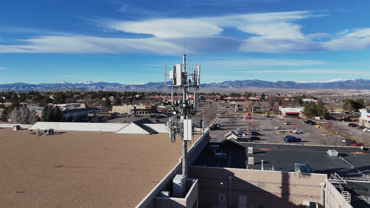 Aerial drone shot showcasing a 360° rotation around a cellular tower mounted on a retail building, highlighting its technology and integration with the structure.