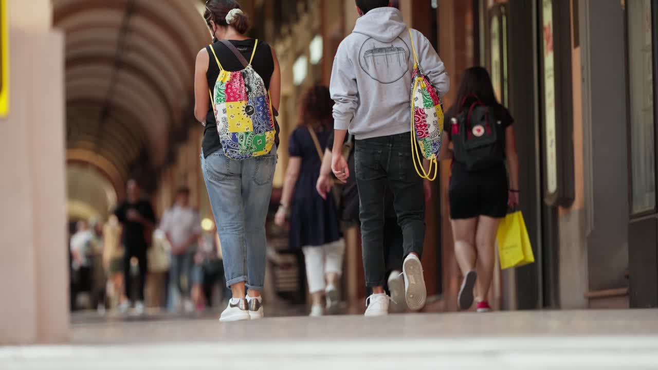 disparo en cámara lenta de ángulo bajo de turistas caminando por bolonia italia en escena anónima