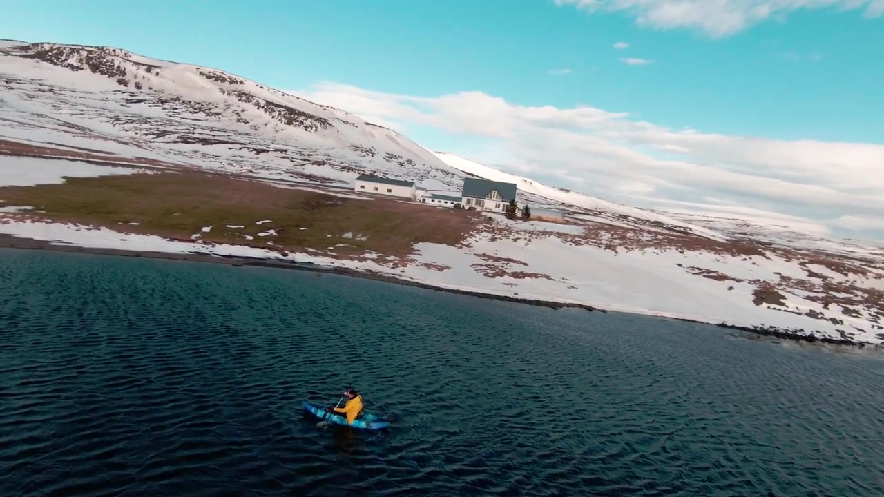 Vista aerea della campagna circondata da montagne e di un uomo del posto che pagaia in kayak