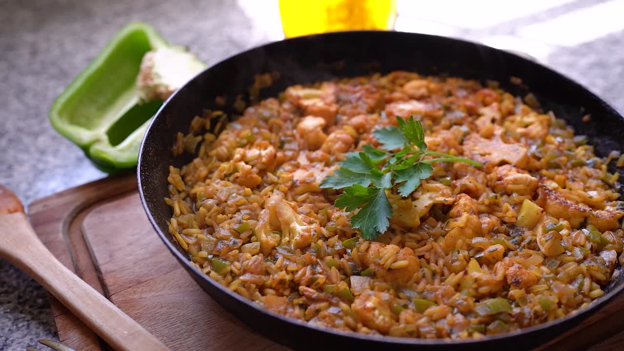 arroz vegetariano cocido caliente con coliflor en una sartén cubierta de perejil fresco