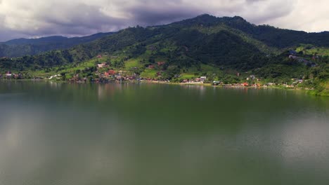 picturesque aerial view of phewa lake with green mountain peak background, drone flying forward in pokhara, nepal