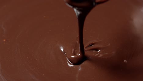 Chef-stirring-mixing-melted-liquid-premium-dark-chocolate-with-whisk-preparation-of-handmade-candies