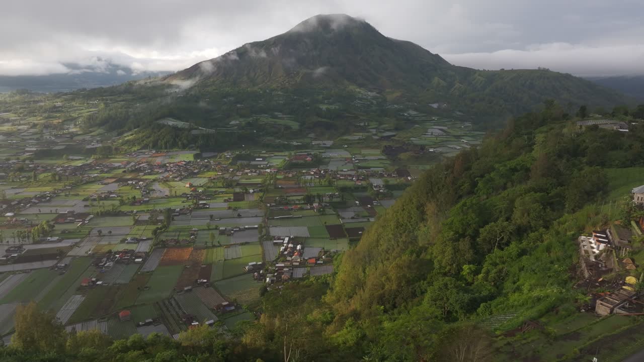 Campi agricoli e foreste di Bali all'alba con un vulcano in lontananza.