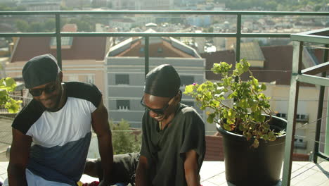 medium shot of gays sitting on walk-out balcony on top floor