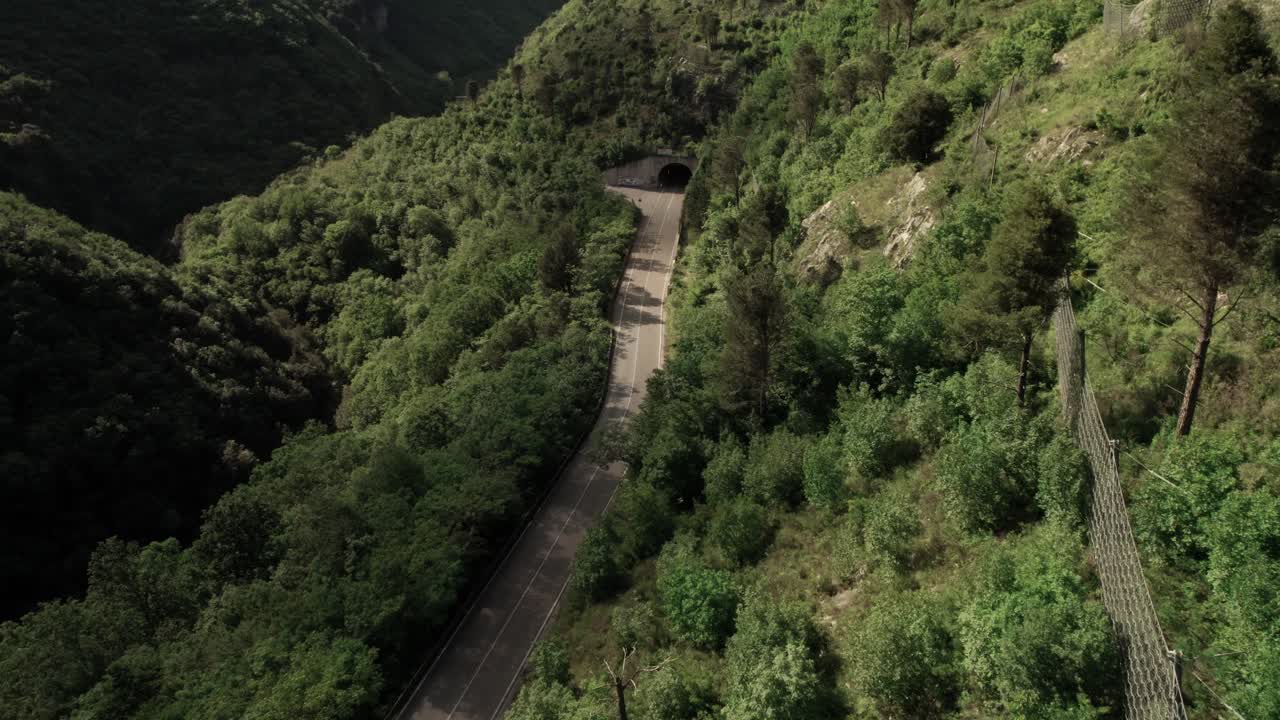 vista aérea hacia adelante de una carretera con túnel en las montañas salvajes