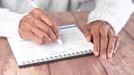 elderly person writing on a calendar