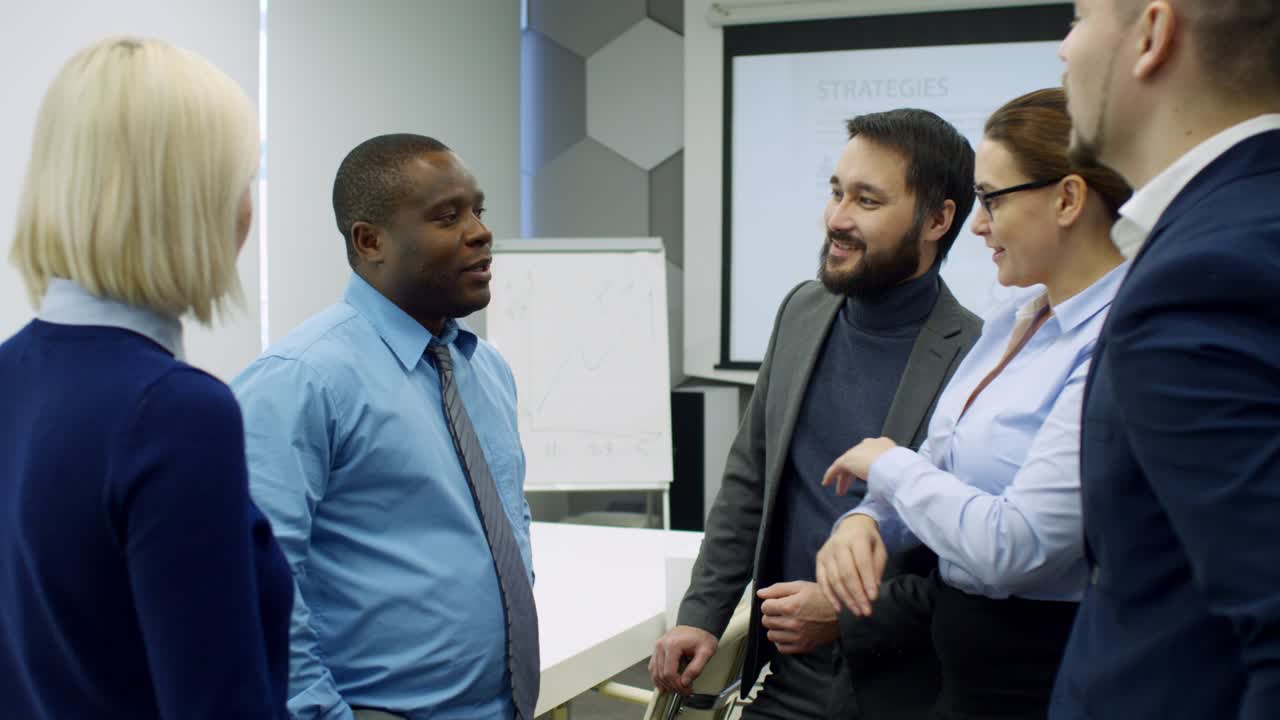 Mixed Raced Coworkers Chatting in Conference Room