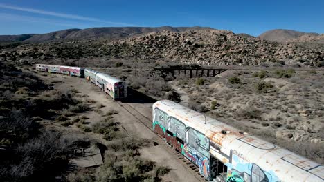 abandoned railroad with train cars covered in graffiti in california desert