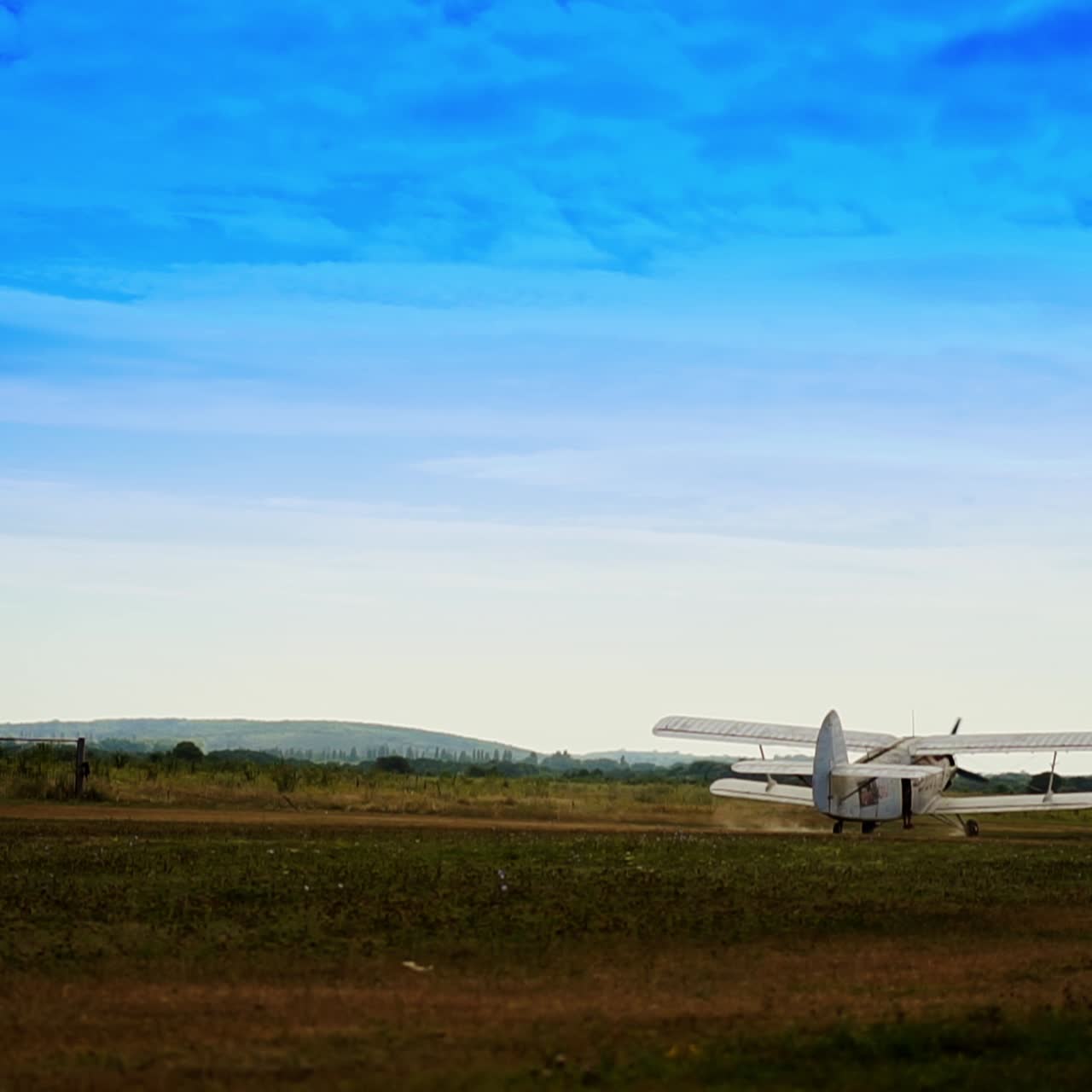 White small aircraft accelerates in the field. Airplane taking off to start a flight