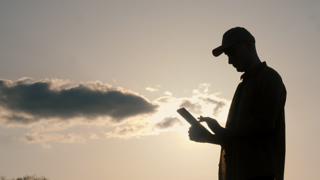Silhouette of a person using a tablet at sunset