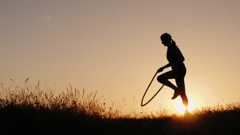 Silueta-De-Una-Mujer---Saltando-A-Través-De-La-Cuerda-Al-Atardecer