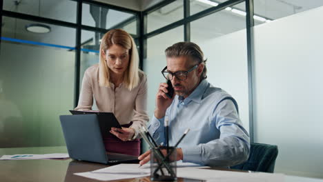 Two-employees-working-together-in-office.-Business-people-brainstorming-laptop