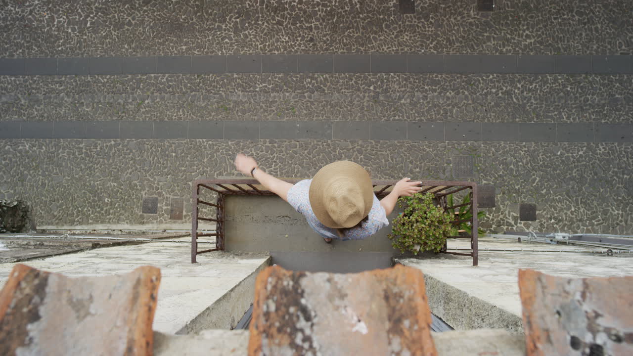 mujer usando un reloj inteligente disfrutando de las vacaciones de verano navegando en línea relajándose en el balcón revisando mensajes con sombrero vista desde arriba