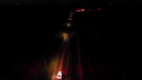 fire trucks on road with lighting lantern at night. aerial tracking shot. flashing red lights during serious traffic accident in american suburb. drone wide shot.