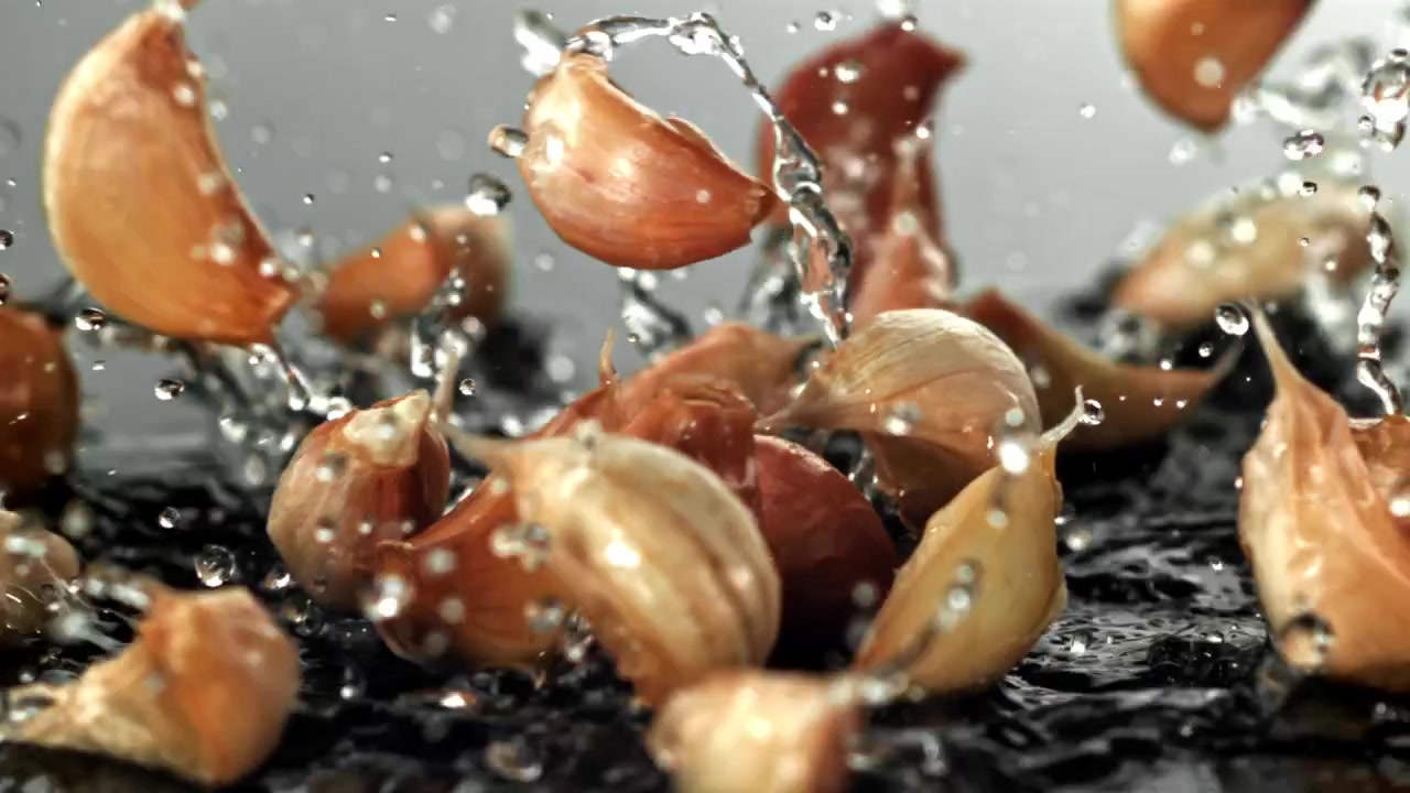 Fresh Garlic Cloves Falling and Splashing into Water in Slow Motion