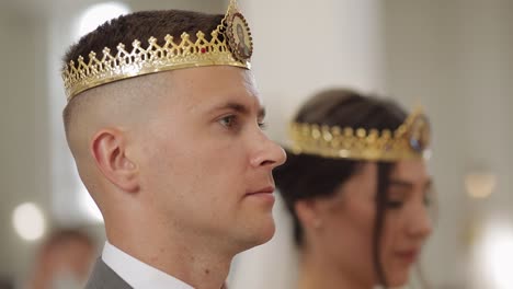 recién casados, la novia y el novio de pie en la iglesia en coronas, ceremonia de boda