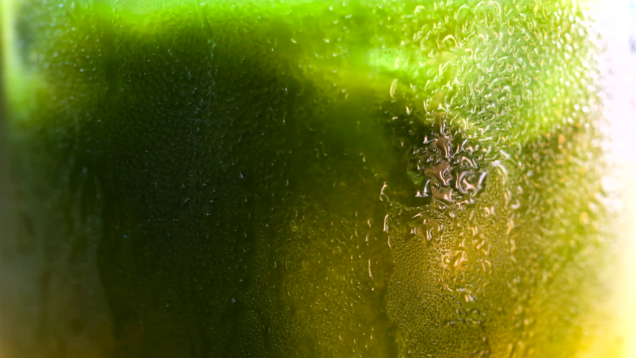 Close up of a glass of an iced orange juice matcha on a table at a cafe