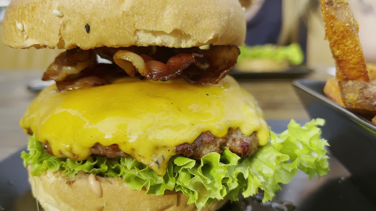deliciosa hamburguesa con queso derretido y carne y ensalada y un tocino con patatas fritas en colonia