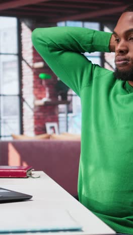 vertical video teleworker fixing his back posture and suffering a muscle cramp at home desk