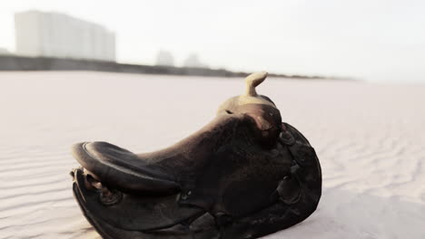 old saddle abandoned on a sandy beach