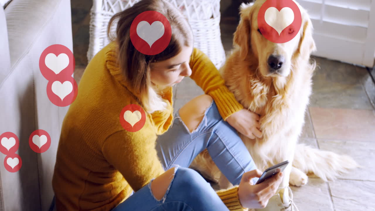 iconos de corazón rojo flotando contra la mujer caucásica usando un teléfono inteligente mientras el perro está sentado en el suelo