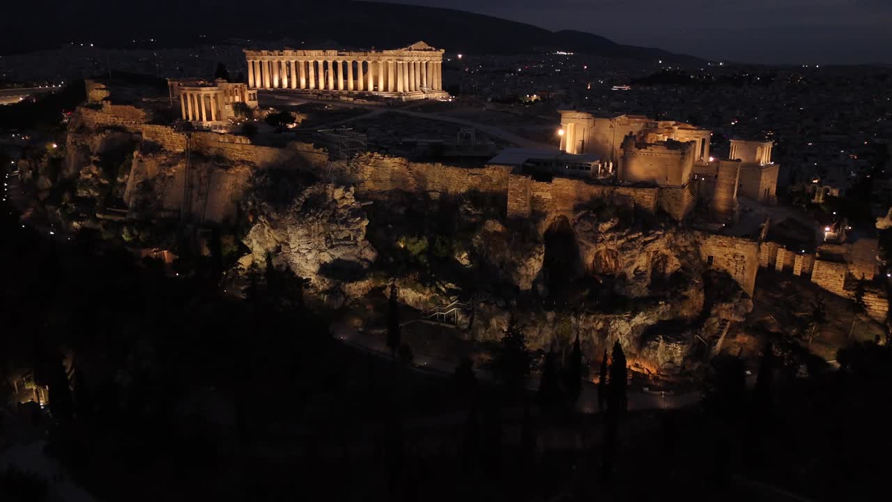 Athens, Aerial view of Beautifully illuminated Acropolis at night from a distance,drone shot approaching towards Panthenon from the side in shimmering lights