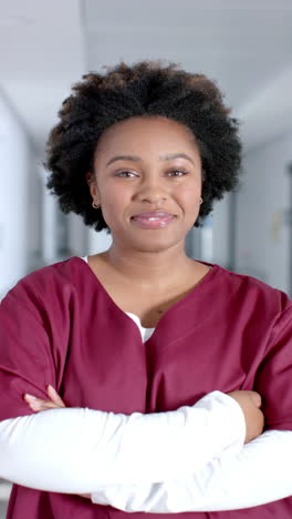vertical video of portrait of happy african american female doctor wearing scrubs, slow motion