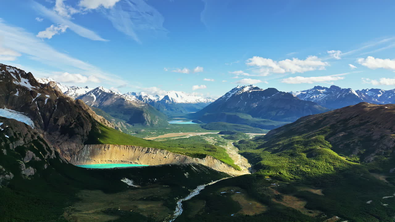 Aerial drone view of a wide valley framed by snow capped Andes mountains and glacial rivers